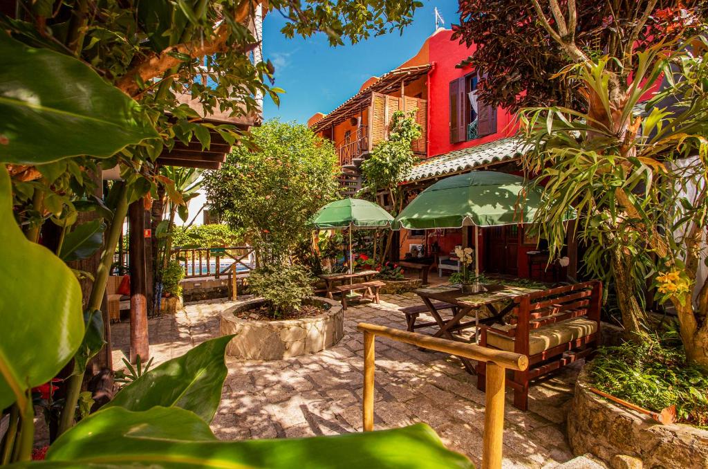 a patio with benches and tables and a red building at Pousada Recanto da Villa in Ilhabela