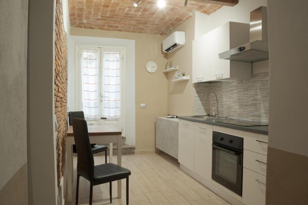 cocina con armarios blancos, mesa y silla en Appartamento La Chicca en Prato