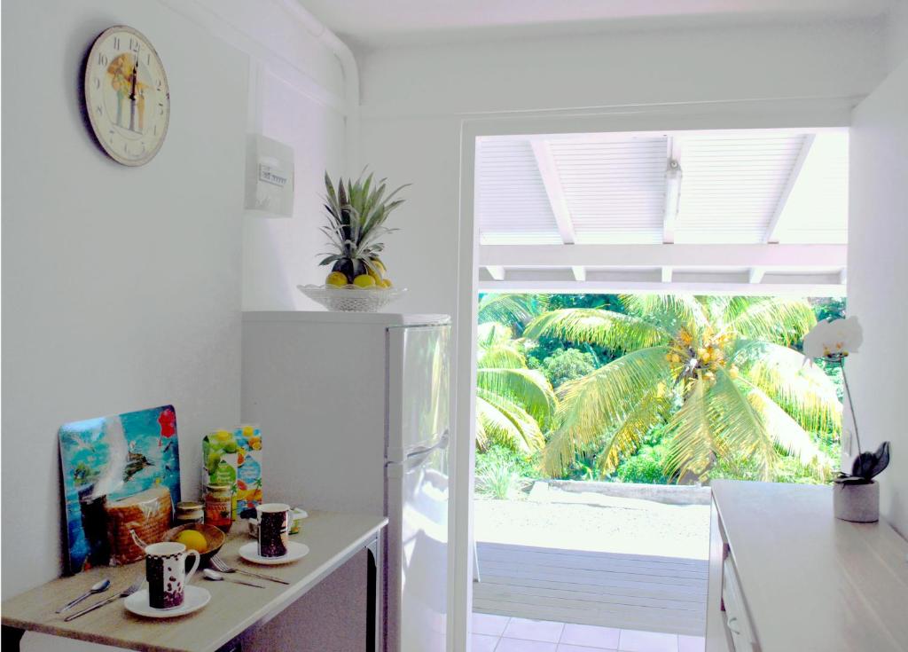 a kitchen with a table and a clock and a window at La Dicossine - La Guadeloupe au naturel ;) in Les Abymes
