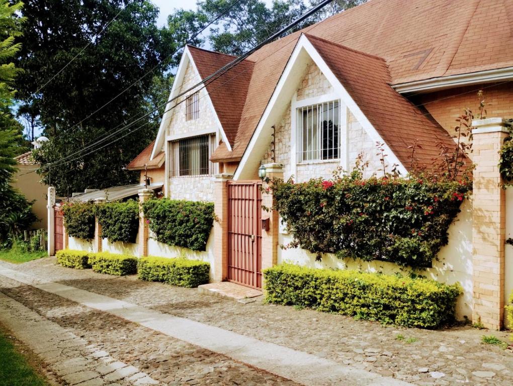 een huis met een rode poort en struiken bij Casa Hacienda Santo Domingo in San Lucas Sacatepéquez