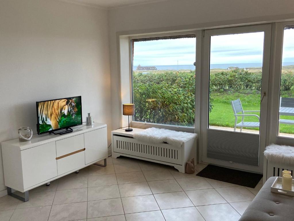 a living room with a tv and a large window at Haus Kampbarg Suite 2-Meer-Blick in Kampen