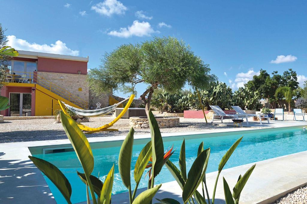 a swimming pool with a hammock next to a house at Casa Farlisa, villa esclusiva con piscina, jacuzzi, palestra, parco giochi, bbq a 5 minuti dal mare in Scicli