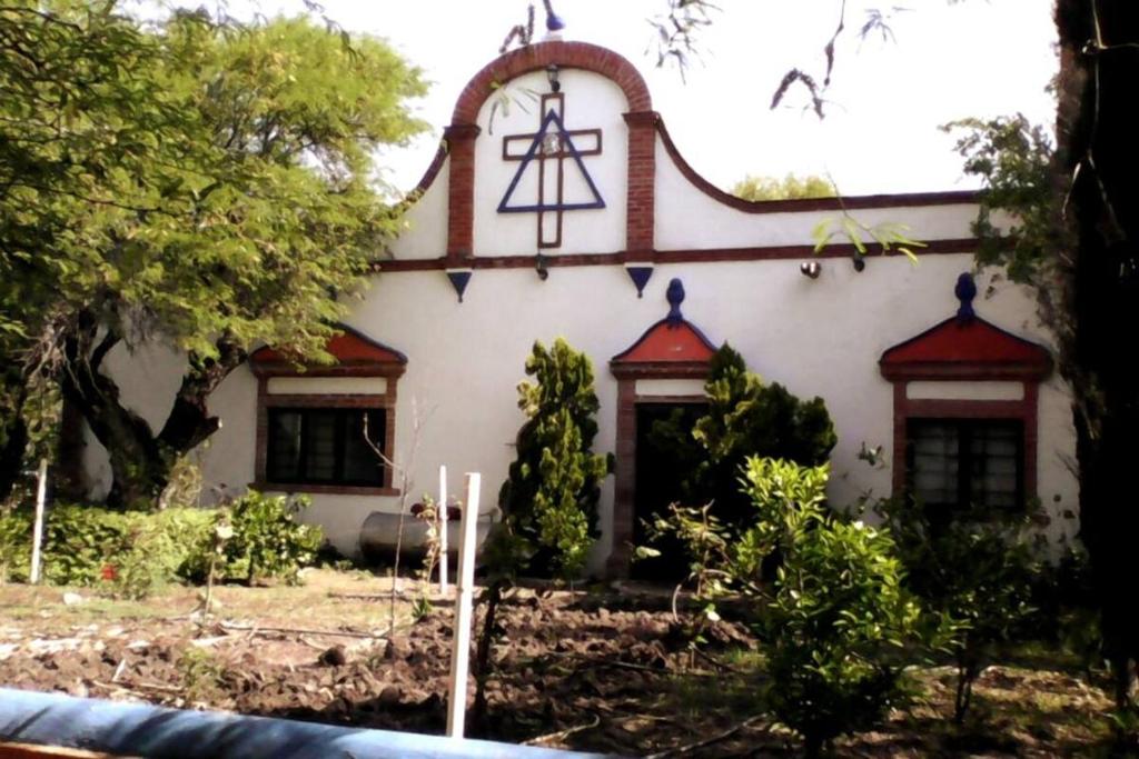 a house with a cross on the side of it at Peña de Bernal Rancho La Trinidad in Cerrito