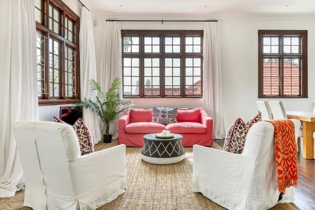 un soggiorno con divano rosso e sedie bianche di Secure & Central: Villa with Views [2 bed both ensuite] a Città del Capo