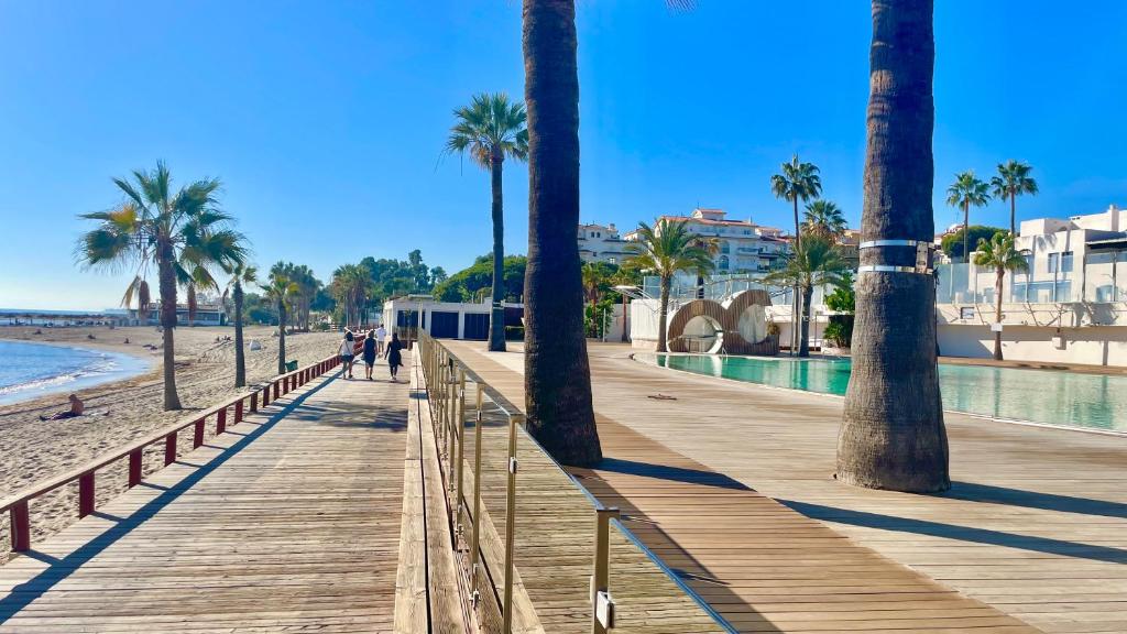 a wooden boardwalk with palm trees on the beach at Playa Del Duque Apartment Ocean Club 1 in Marbella