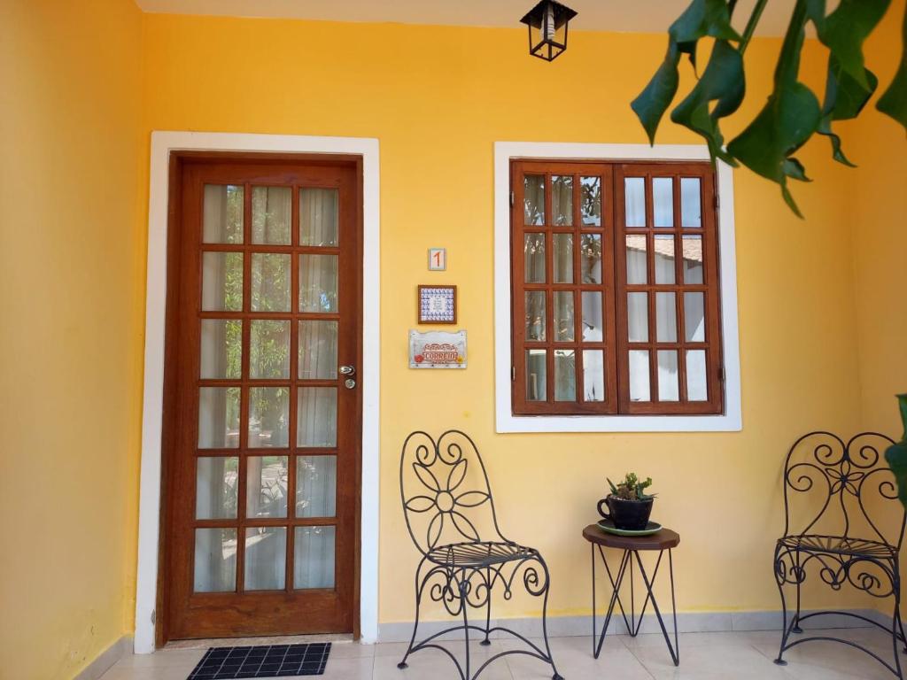 two chairs in front of a yellow wall with windows at Apartamento em Lencois No 01- Primavera in Lençóis