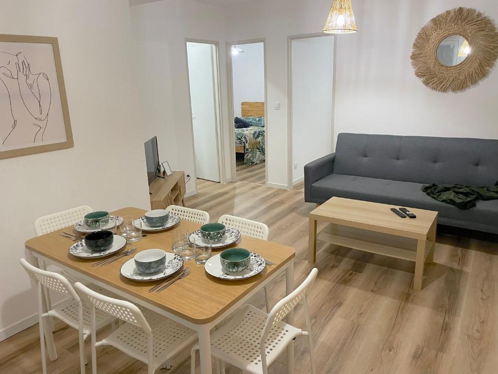 een woonkamer met een tafel en stoelen en een bank bij ღ Le Saintois • Au cœur de ville, Spacieux & Wifi in Saintes