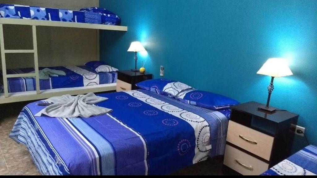 2 Betten in einem Zimmer mit blauen Wänden in der Unterkunft HOSTAL DEL SOL in Manuel Elordi