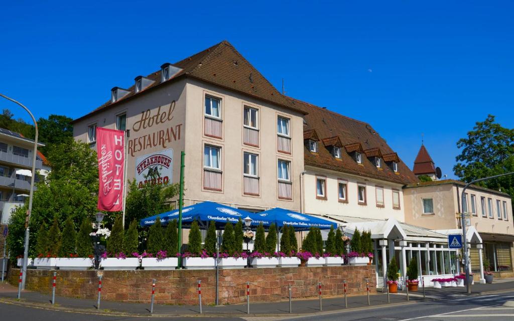 a large building with blue umbrellas in front of it at Hotel Schäffer - Steakhouse Andeo in Gemünden