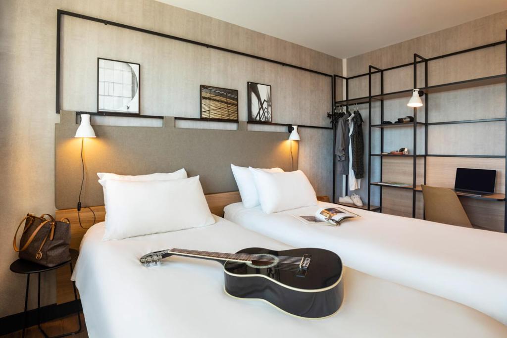 a hotel room with a guitar on a bed at ibis Strasbourg Centre Les Halles in Strasbourg