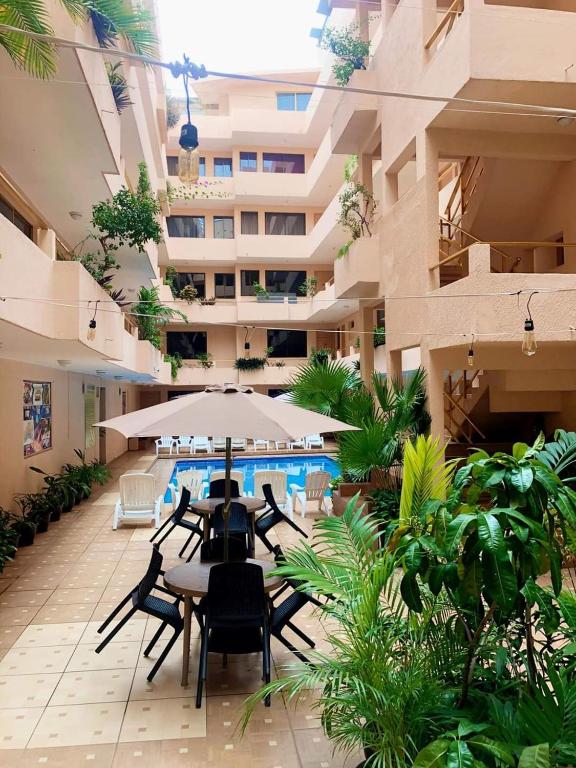 an apartment patio with tables and an umbrella and a pool at Hotel Delfines Del Mar in Acapulco