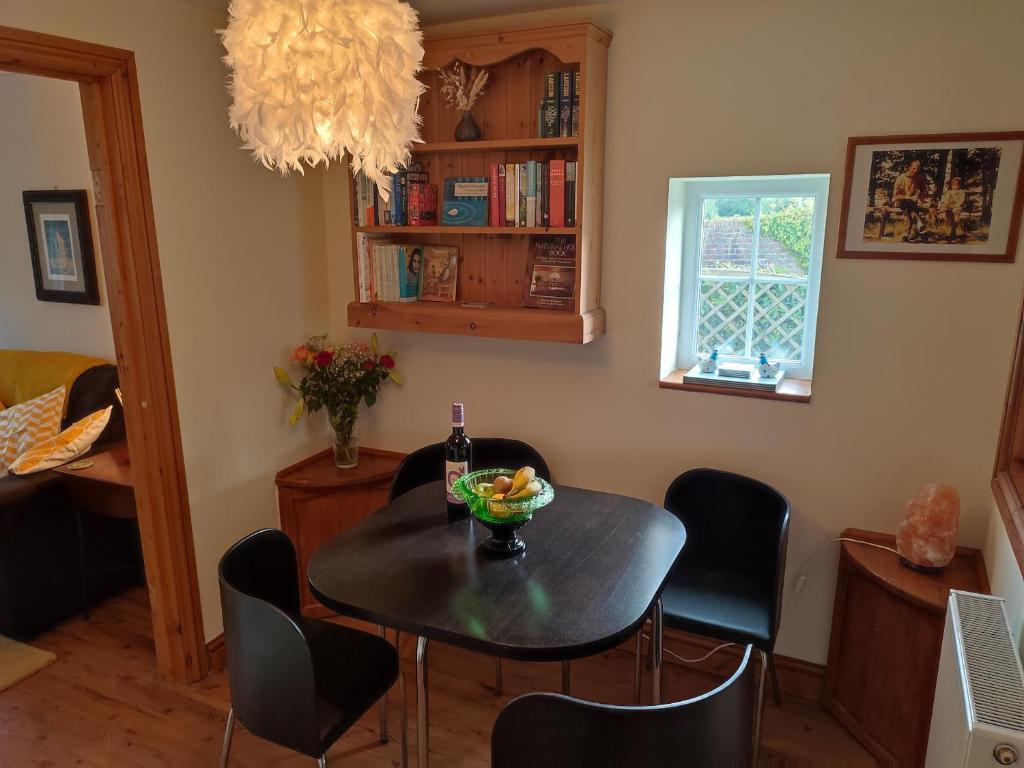 - une salle à manger avec une table, des chaises et une bouteille de vin dans l'établissement Pretty cottage in the heart of Tenterden, à Kent