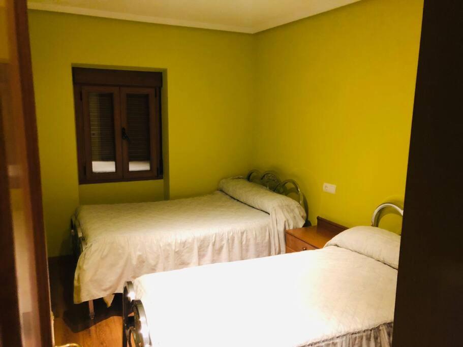 2 camas en una habitación con paredes amarillas en La Casucha, en Caboalles de Abajo