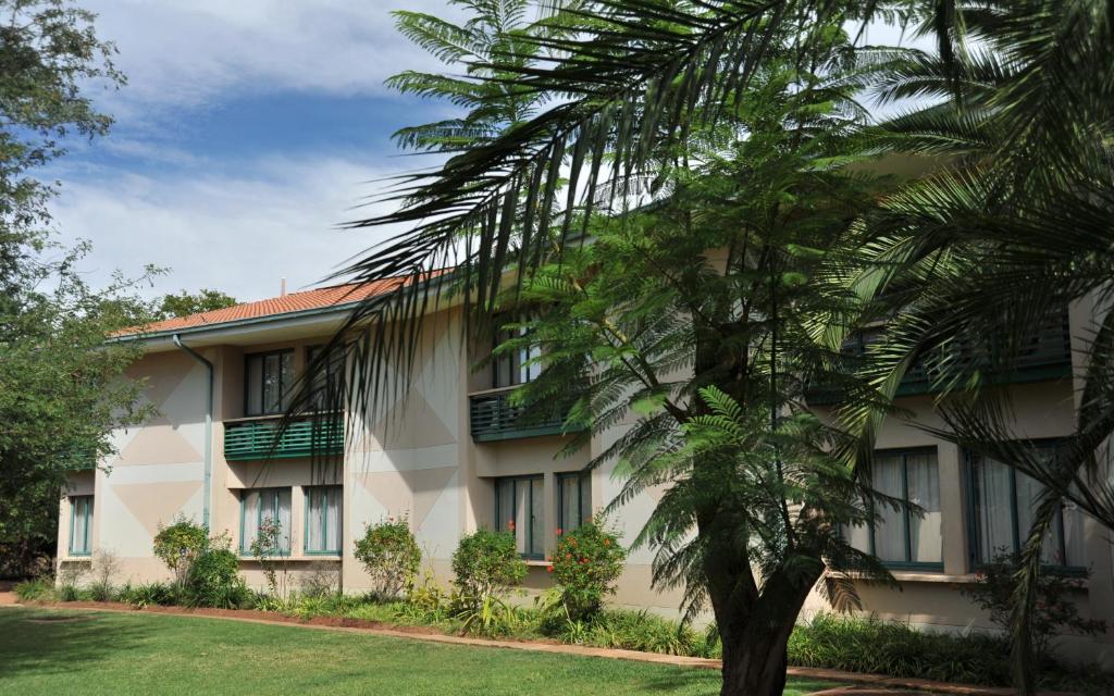 a building with a palm tree in front of it at Cresta Bosele Hotel in Selebi-Pikwe