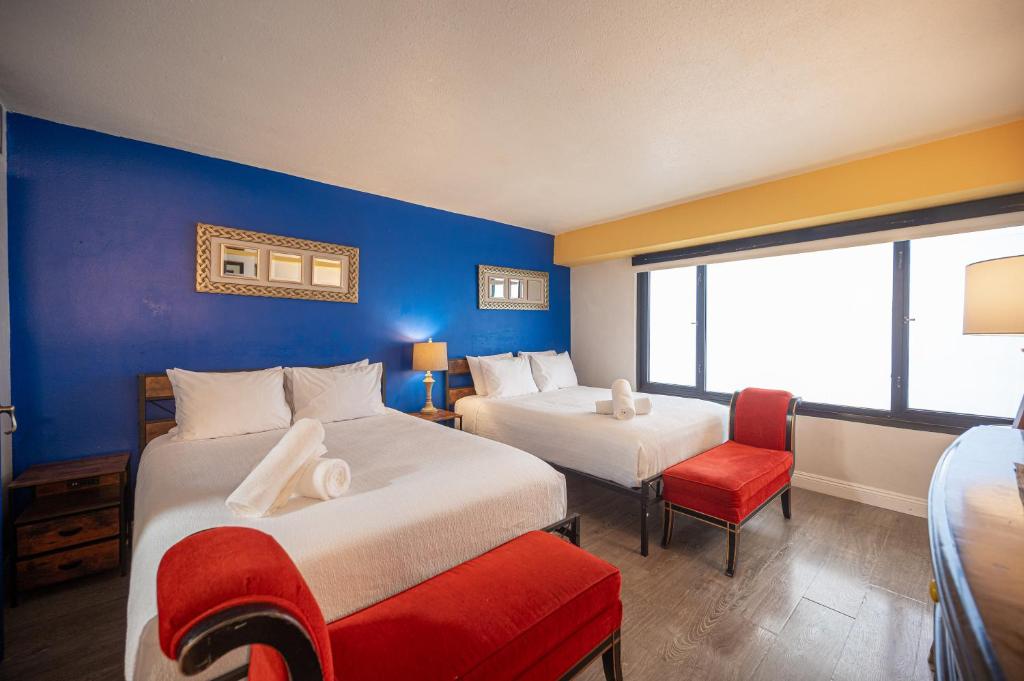 a hotel room with two beds and a red chair at Stay Together Suites on The Strip - 1 Bedroom Suite 1012 in Las Vegas