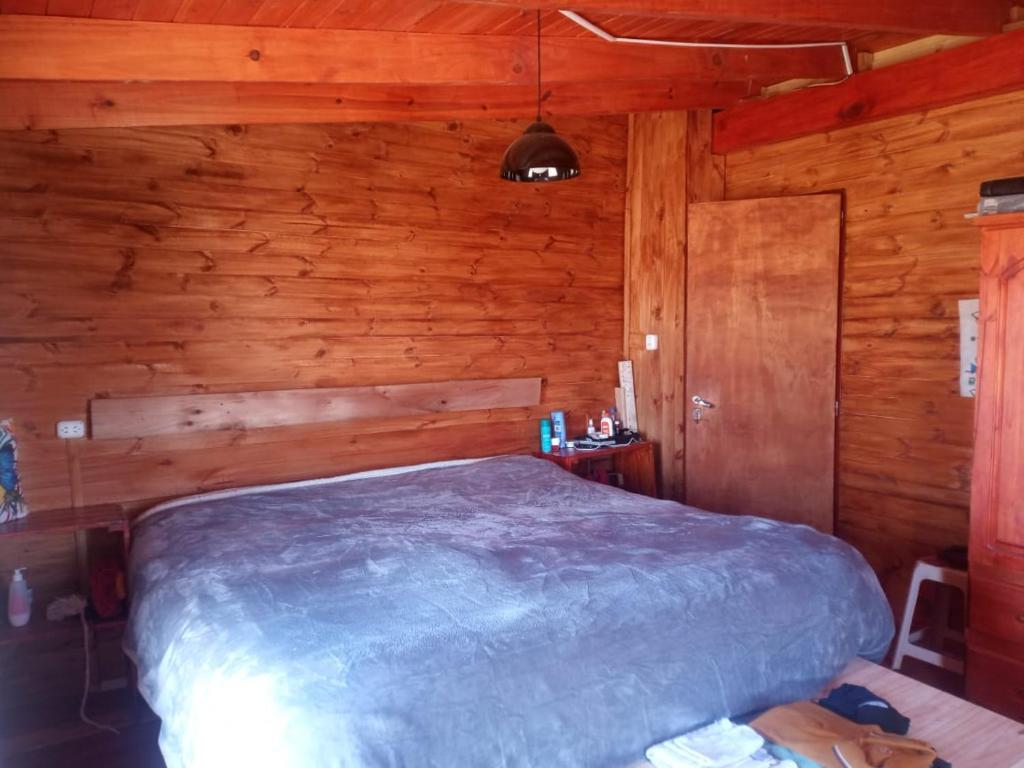 ein Schlafzimmer mit einem Bett in einer Holzhütte in der Unterkunft Cabaña Sion in Puerto Madryn