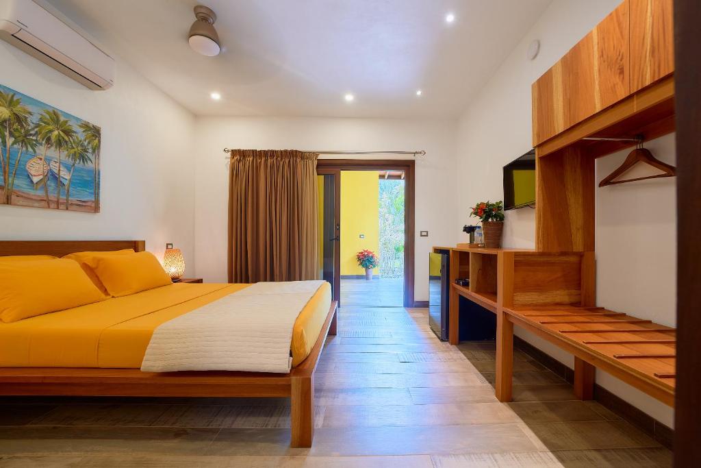 - une chambre avec un grand lit jaune et une télévision dans l'établissement Oasi, à Cahuita