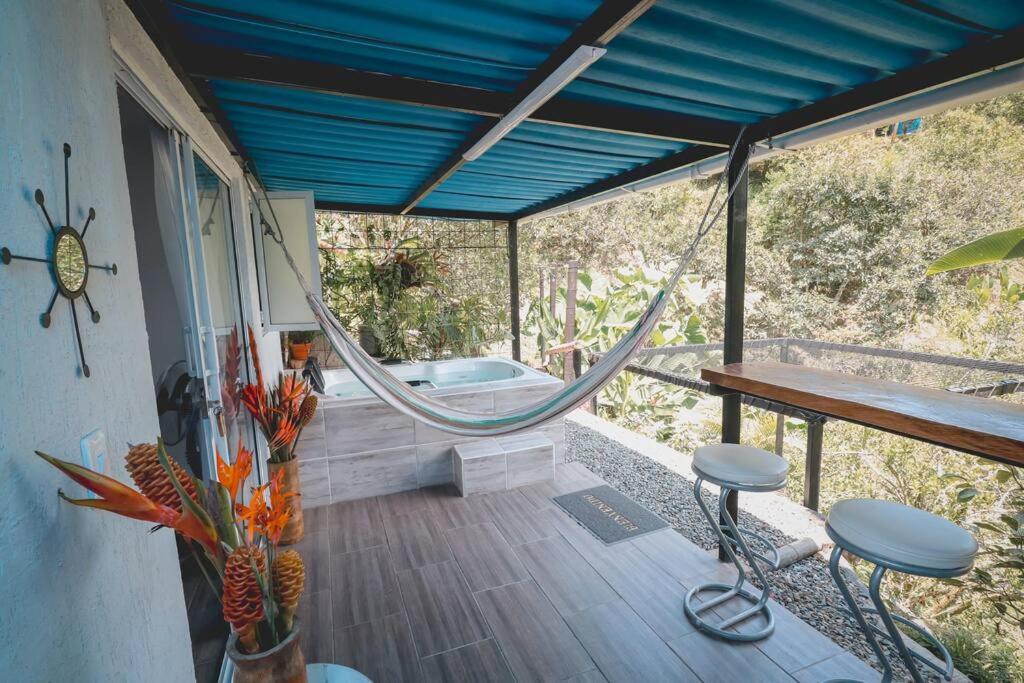 a porch with a hammock and a bath tub at Cabaña / hotel campestre en Manizales para pareja in Manizales