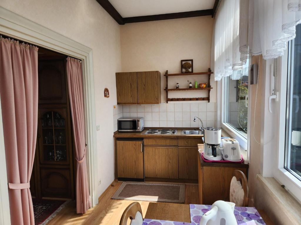 Elle comprend une petite cuisine avec des placards en bois et une fenêtre. dans l'établissement Apartment 31, im Zentrum Braunlage, à Braunlage