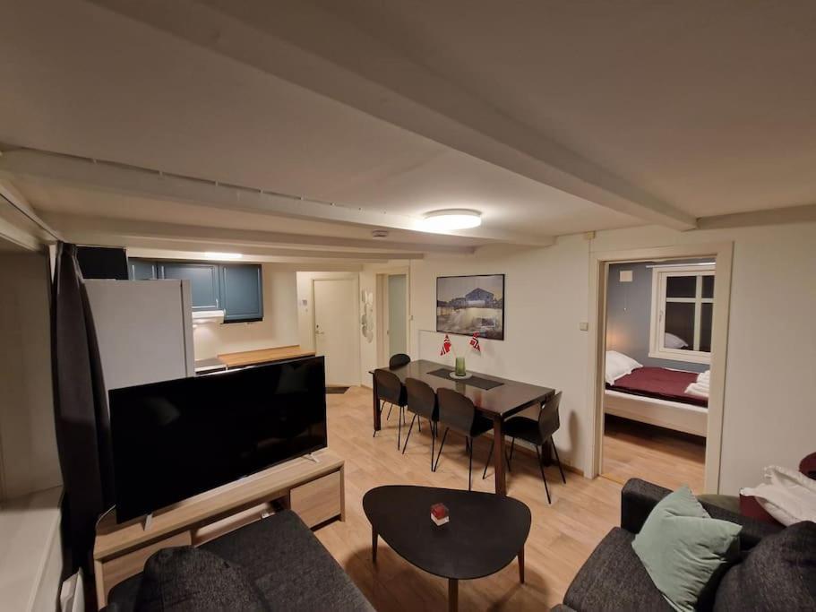 uma sala de estar com um sofá e uma mesa com cadeiras em Apartment next to the bridge em Tromsø