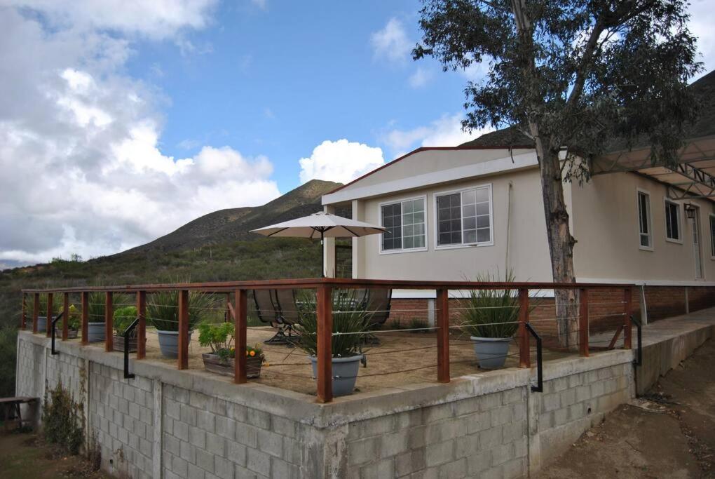 a deck with potted plants and an umbrella on a house at Casa de campo en ruta del vino in Villa de Juárez