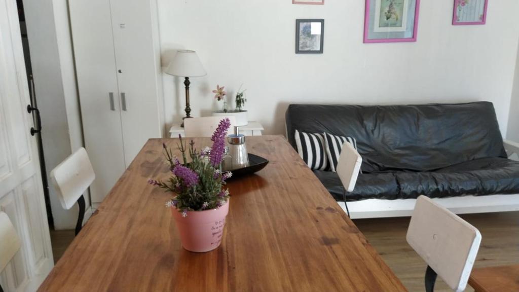 uma sala de estar com uma mesa de madeira com um vaso de flores em Cabaña a pasos del lago em Tandil