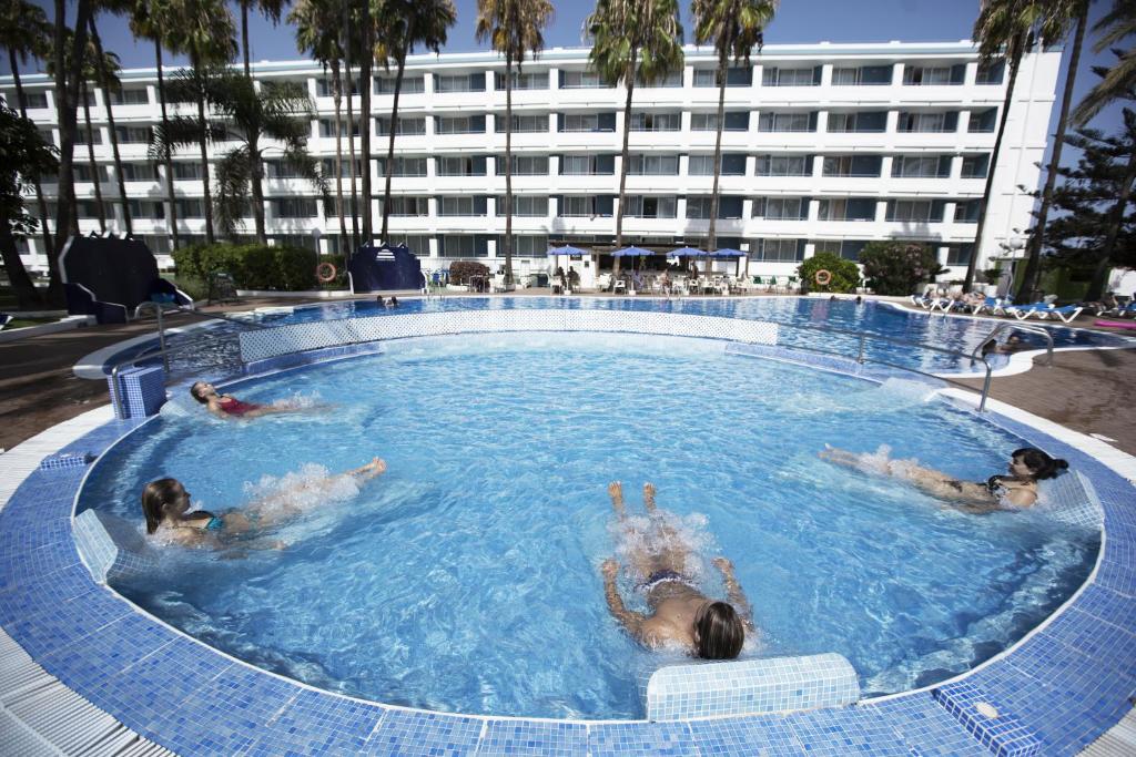 a man and a woman swimming in a pool at Playa Del Sol - Adults Only in Playa del Ingles