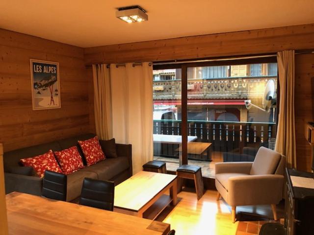 a living room with a couch and a table and a window at Appartement 2 chambres centre MORZINE in Morzine