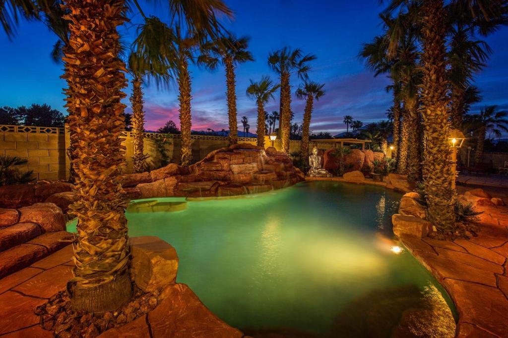 a pool with palm trees in a backyard at night at Z House in Las Vegas