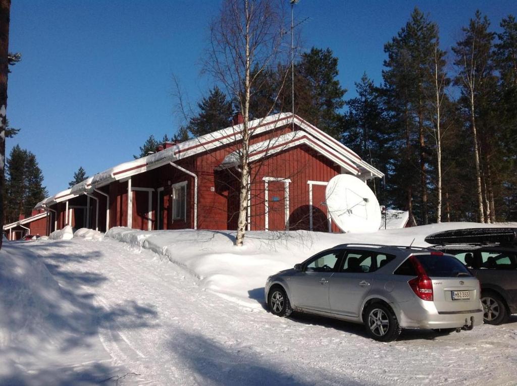 un coche aparcado frente a una casa en la nieve en Koli Country Club, en Hattusaari