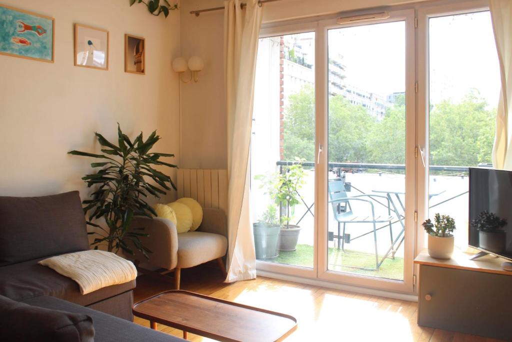 a living room with a couch and a sliding glass door at Crossing cocoon with balcony and clear view in Paris