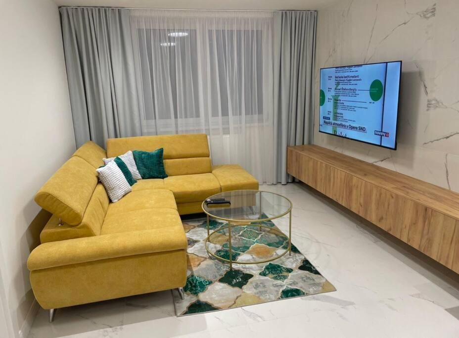 a living room with a yellow couch and a tv at Apartmán v meste Michalovce in Michalovce