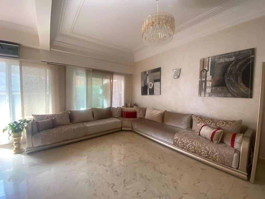 un ampio soggiorno con divano e lampadario a braccio di Appart bien équipé avec jardin privé à California a Casablanca