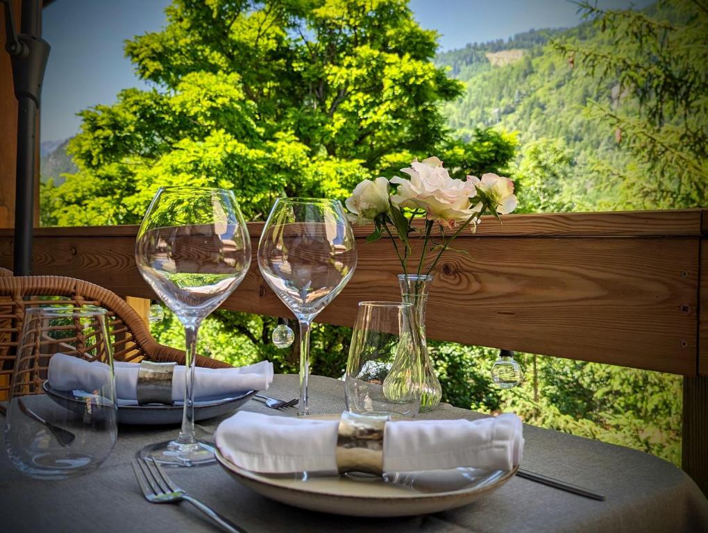 een tafel met wijnglazen en een vaas met bloemen bij Auberge Saint Antoine in Pelvoux