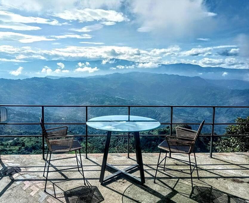 einen Tisch und Stühle auf einem Balkon mit Aussicht in der Unterkunft Suite entre los árboles Hotel Portal 360 in Nocaima