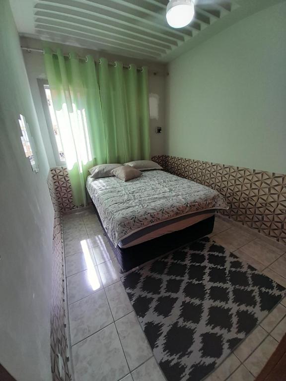 um quarto com uma cama com cortinas verdes e um tapete em Apartamento no centro de Cuiabá a 4 km do aeroporto em Cuiabá