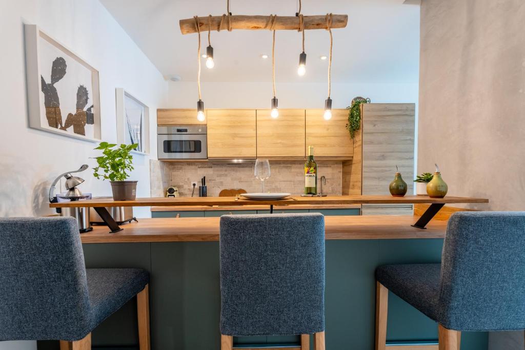 une cuisine avec un comptoir en bois et des chaises bleues dans l'établissement Charmant T2 à proximité de Castellane - Le Bistrot, à Marseille