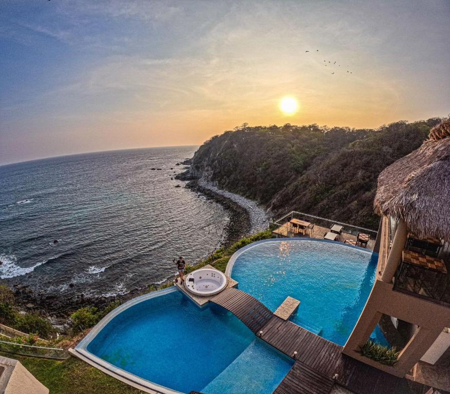 CuatunalcoにあるPacific King Hotelのスイミングプール付きのリゾートから海の景色を望めます。