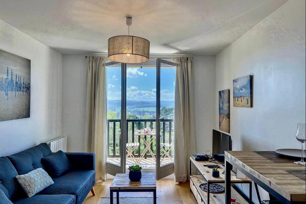 un salon avec un canapé bleu et une grande fenêtre dans l'établissement Appartement Lassay - Welkeys, à Blonville-sur-Mer