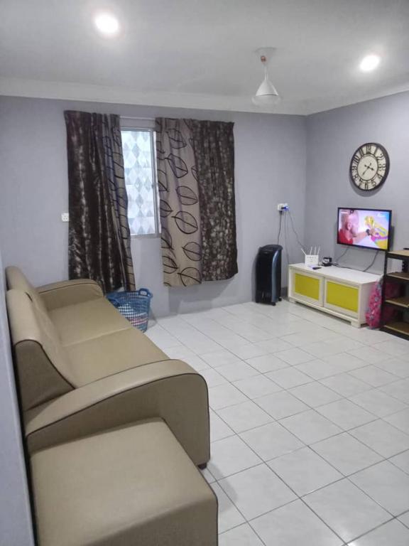 a living room with a couch and a tv at Orchid Homestay in Labuan