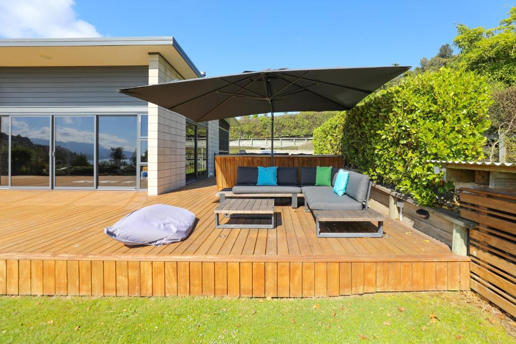 a wooden deck with a couch and an umbrella at Lake Tarawera Gem in Rotorua