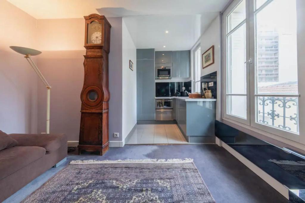 un salon avec une horloge grand-père et une cuisine dans l'établissement Spacious 1 Bedroom Apartment in Paris, à Paris