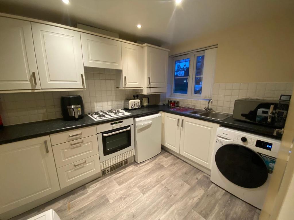 uma cozinha com armários brancos e um forno com placa de fogão em Lovely 2 bed apartment in Crosby em Liverpool