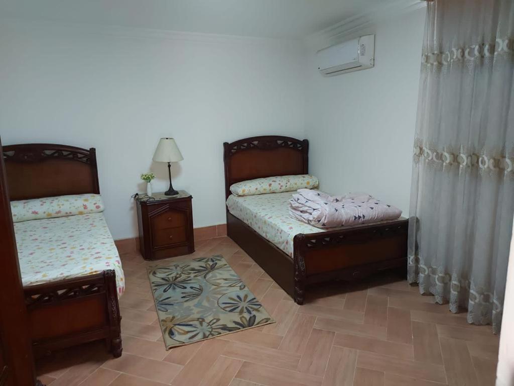 1 dormitorio con 2 camas y 2 mesitas de noche en Ground floor villa with private garden, parking and shared swimming pool, en Al ‘Ajūzah