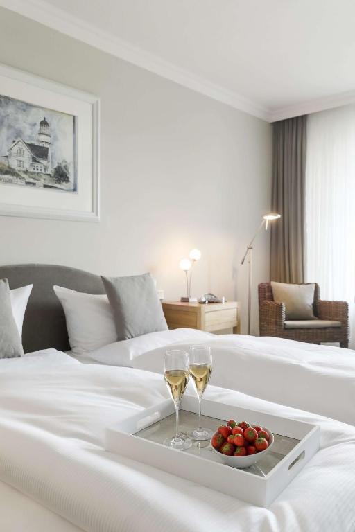 a white bed with two glasses of wine and a tray of fruit at Dorint Strandresort & Spa Westerland/Sylt in Westerland