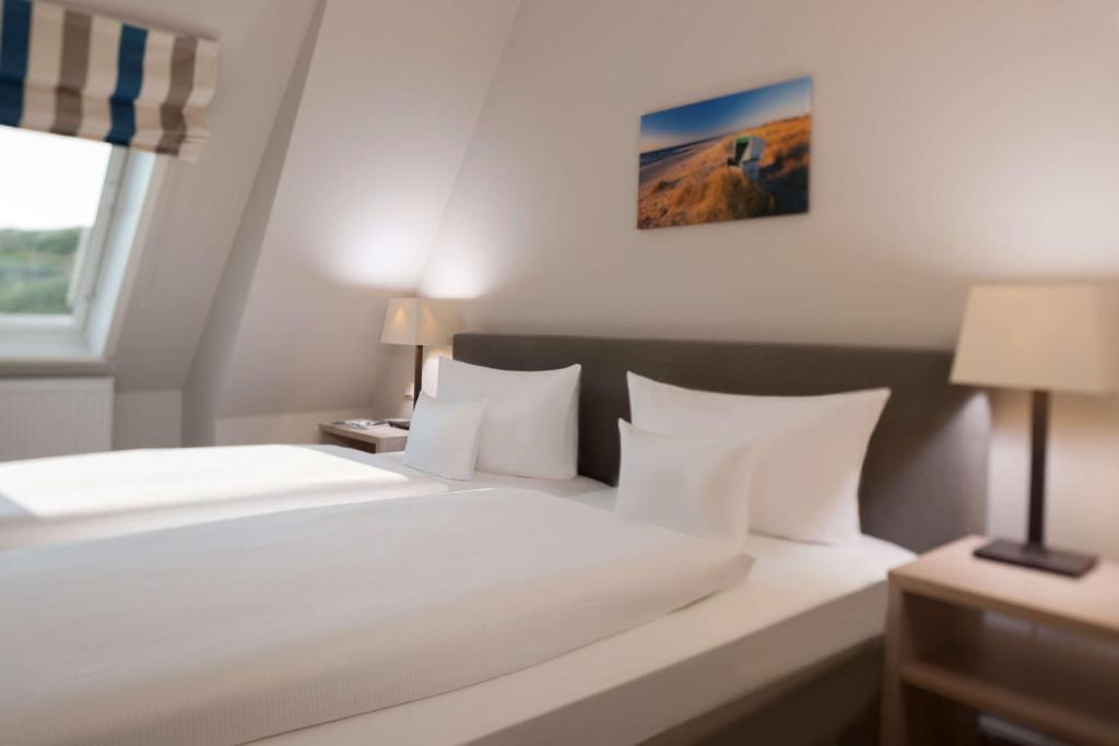 a bedroom with a large white bed with white pillows at Dorint Strandresort & Spa Westerland/Sylt in Westerland