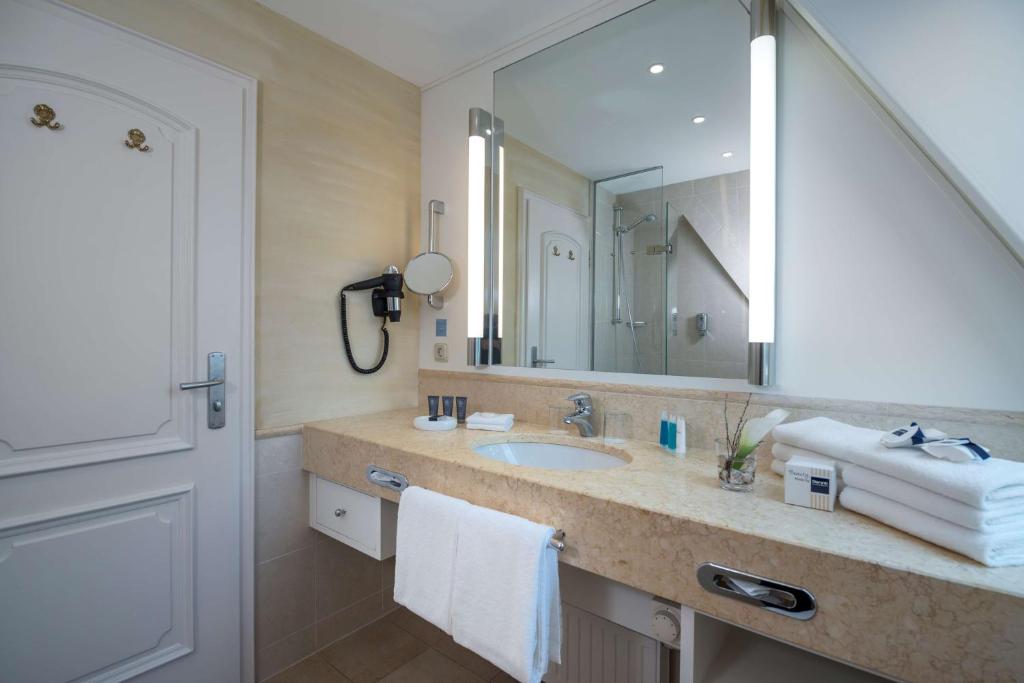 a bathroom with a sink and a large mirror at Dorint Strandresort & Spa Westerland/Sylt in Westerland