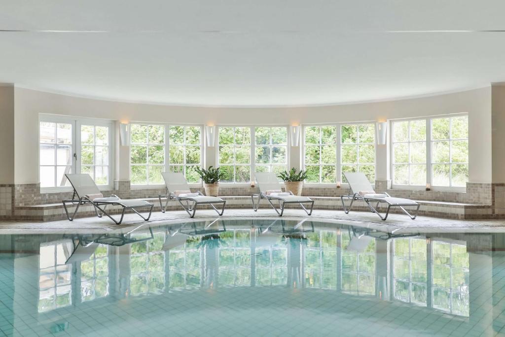a large pool in a building with chairs and windows at Dorint Strandresort & Spa Westerland/Sylt in Westerland