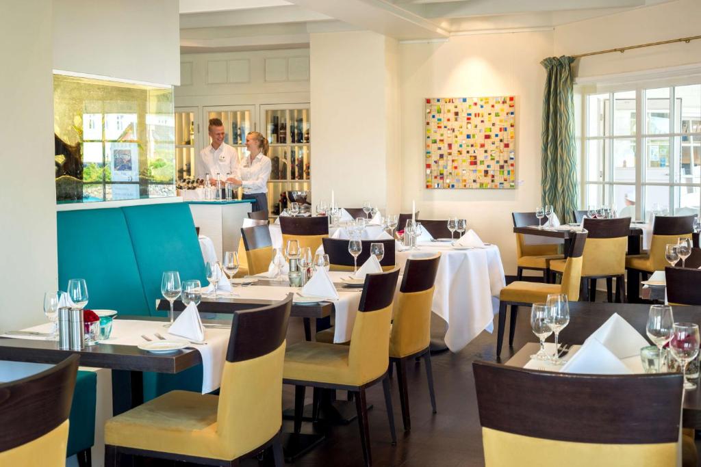 a restaurant with tables and chairs and a bar at Dorint Strandresort & Spa Westerland/Sylt in Westerland
