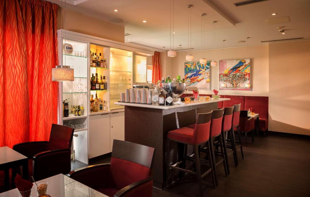 a bar in a restaurant with red chairs at Dorint Strandresort & Spa Westerland/Sylt in Westerland